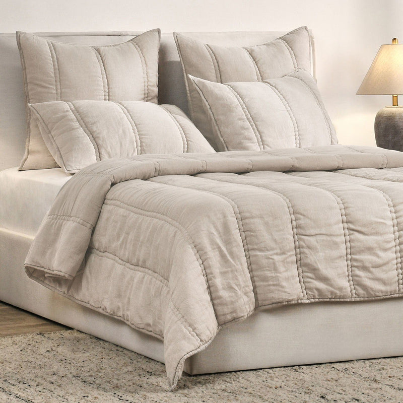 Light taupe quilt set with padded quilt cover and three decorative pillows on bed