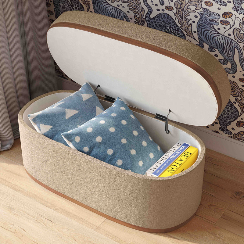 Beige boucle oval storage ottoman with open lid, showing blue polka-dot items inside