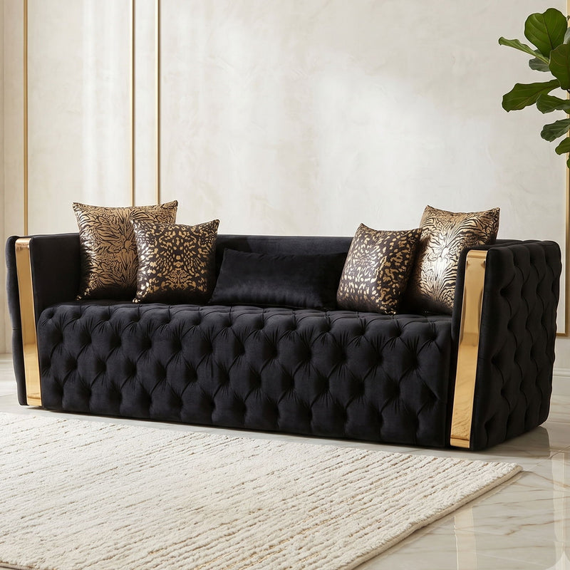 Front view of black tufted sofa with gold-finish arms and four patterned cushions
