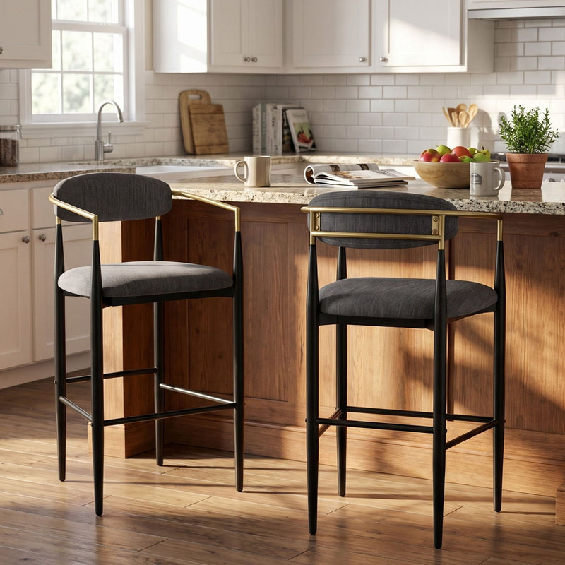 Two charcoal upholstered bar stools with slim black frames and gold-tone arm accents at a kitchen counter