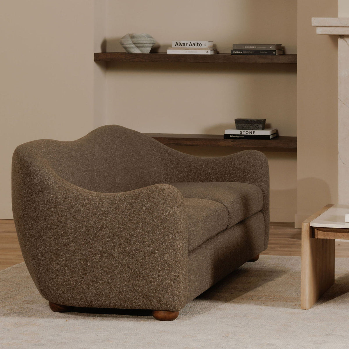 Brown Bria sofa viewed at an angle, showing its curved back and rounded arm