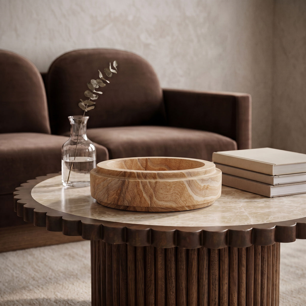 Light brown sandstone bowl filled with dried botanicals on a surface.