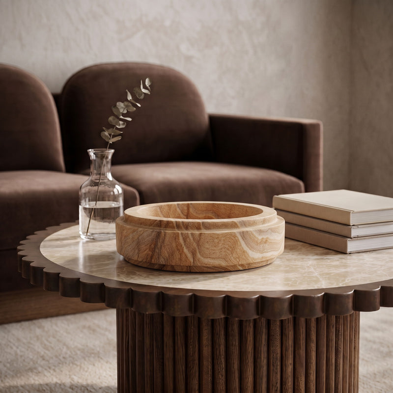 Light brown sandstone bowl filled with dried botanicals on a surface.