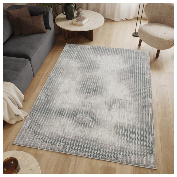 Gray area rug with abstract 3D geometric pattern and bordered edge.
