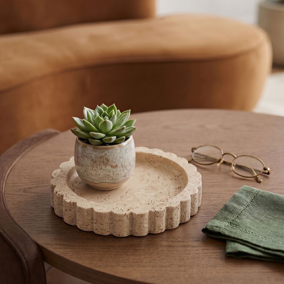 Beige travertine serving tray with scalloped rim on a wooden table