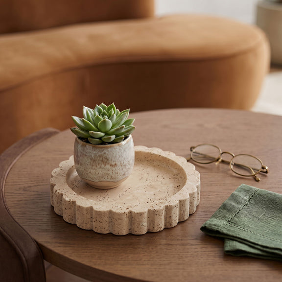 Beige travertine serving tray with scalloped rim on a wooden table