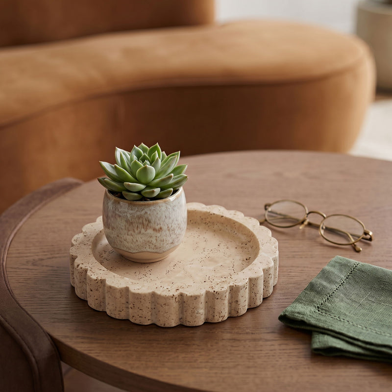 Beige travertine serving tray with scalloped rim on a wooden table