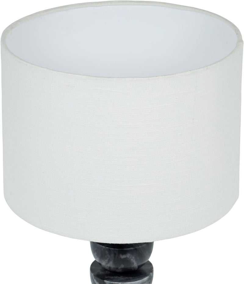 Table lamp close-up: white fabric drum shade over dark marble base with brass finial