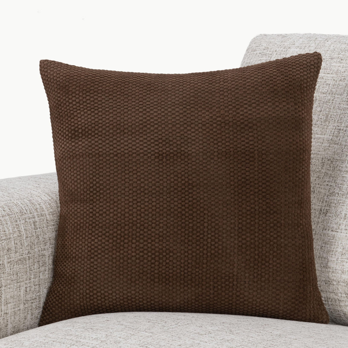 Coffee brown woven square pillow on light upholstered seating