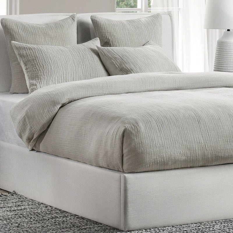 Light gray pillow shams layered on a bed, textured crinkle fabric and square corners