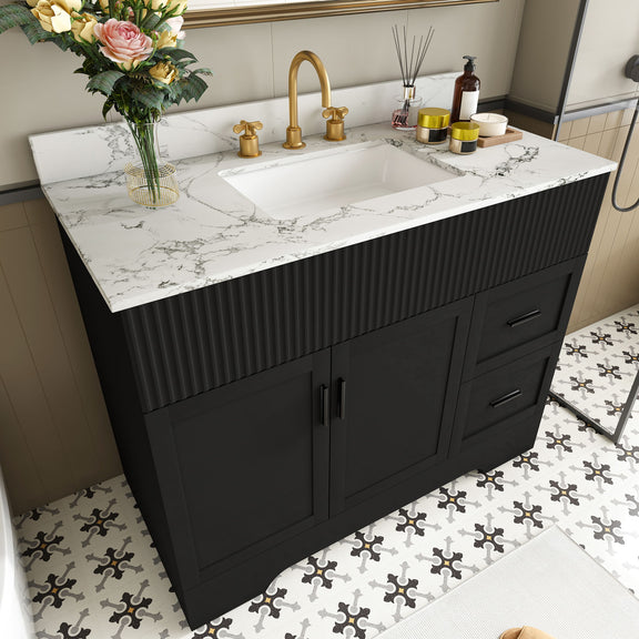 Black bathroom vanity with fluted cabinet, marble-style countertop and sink, three faucet fixtures