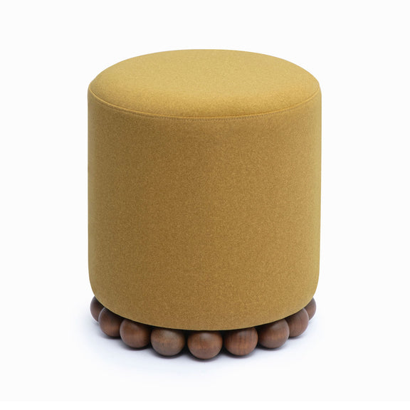 Round upholstered ottoman in light brown with beaded wooden base, side view