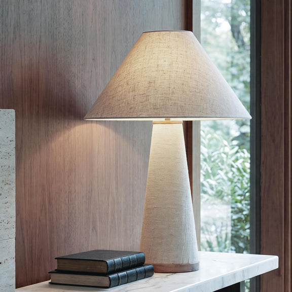 Beige fabric table lamp with conical shade and tapered metal base, wood-tone ring