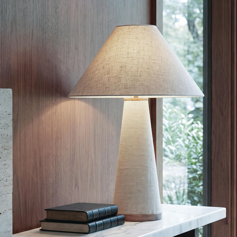 Beige fabric table lamp with conical shade and tapered metal base, wood-tone ring