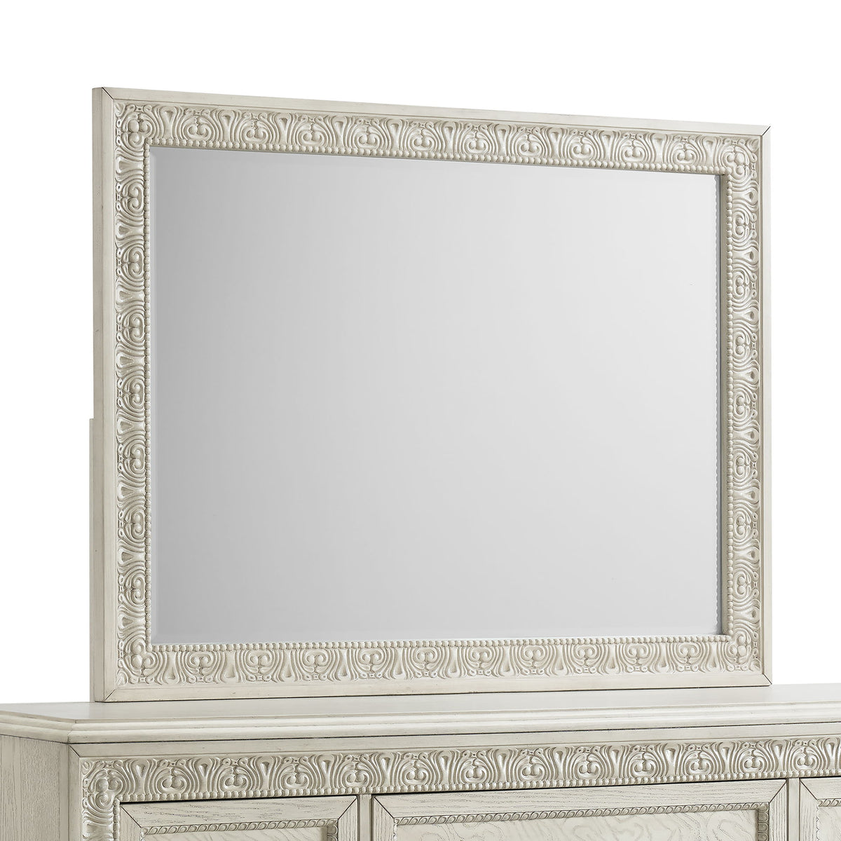 Ornate white mirror with carved frame on top of a dresser.