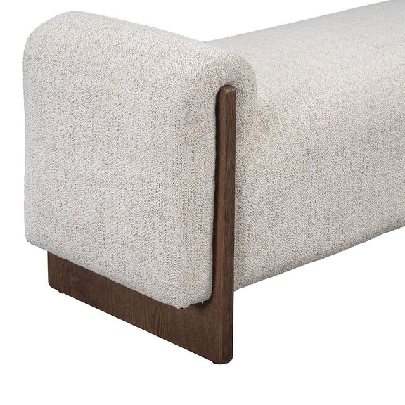 Upholstered bench side view with rounded arms, light sand fabric and dark wood legs