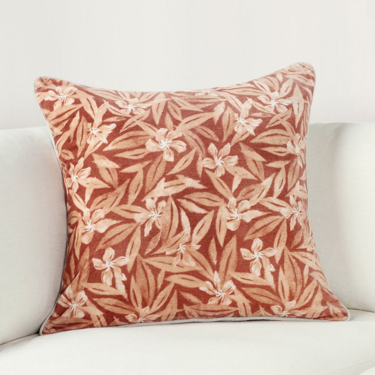Rust and cream botanical print square throw pillow on light couch, 22x22 in