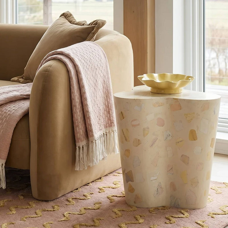 Beige terrazzo-pattern side table with rounded drum shape and flat top