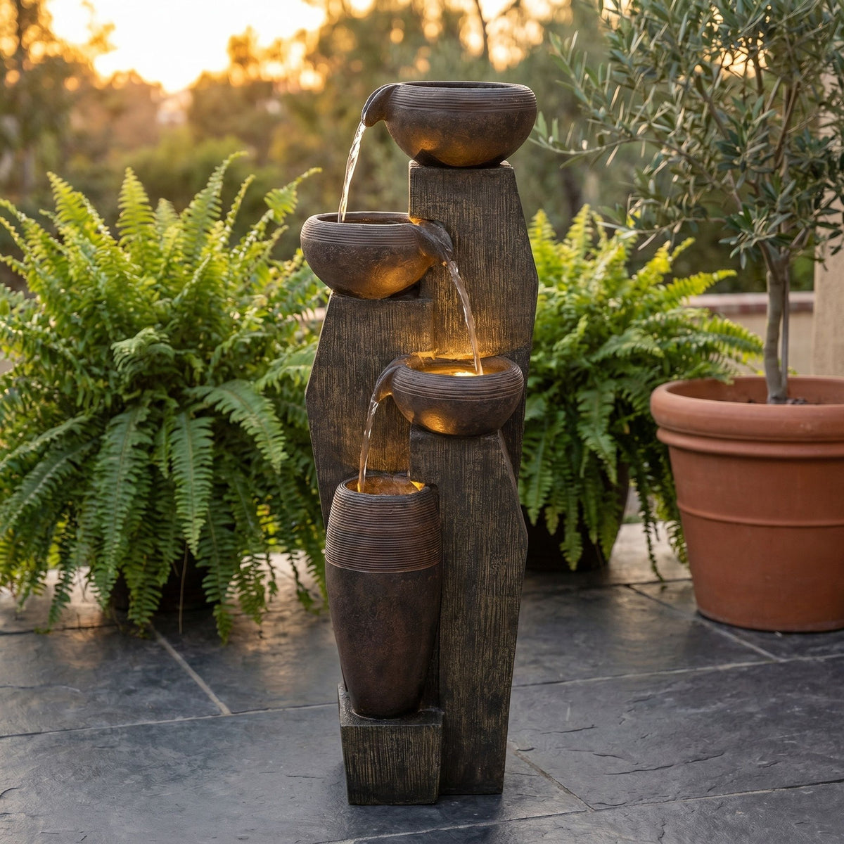 Brown four-tier water fountain with cascading bowls and warm lights