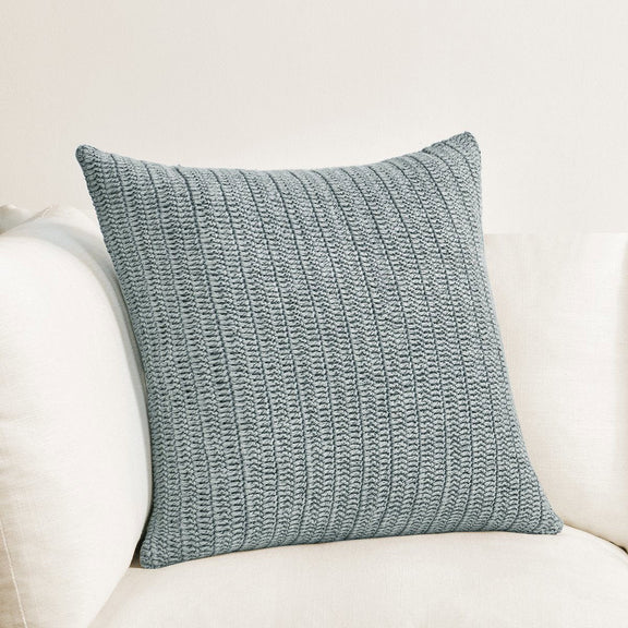 Blue-gray textured woven lumbar pillow on sofa, square cornered rectangular shape
