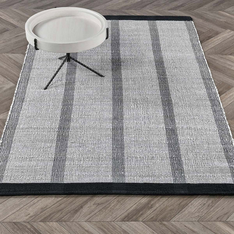 Ivory stripe rug with vertical gray and muted green stripes, navy border; white roll nearby.