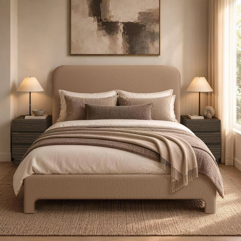 Light brown upholstered bed with pillows, quilt, and throw blanket on slat base