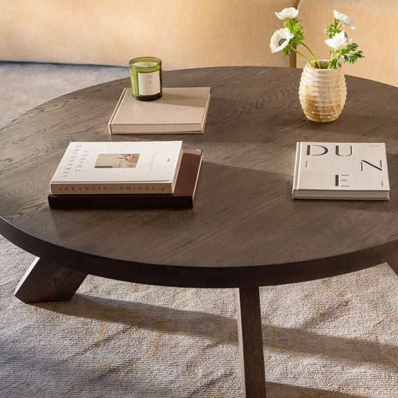 Round dark brown coffee table with wood-grain surface and angled leg base