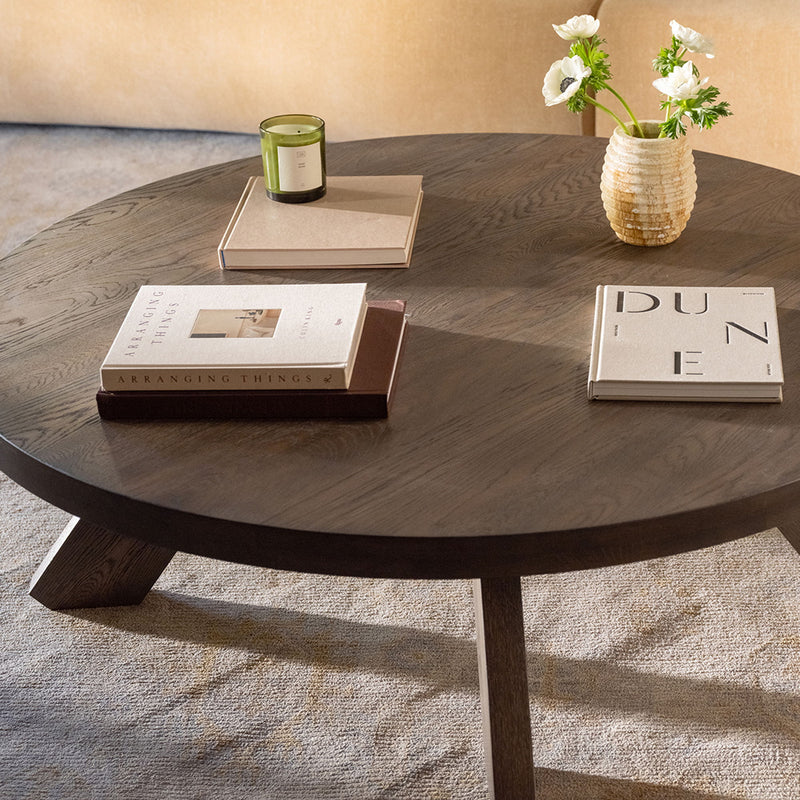 Round dark brown coffee table with wood-grain surface and angled leg base