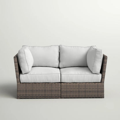 Dark brown wicker loveseat with light gray seat and back cushions, two bolster pillows
