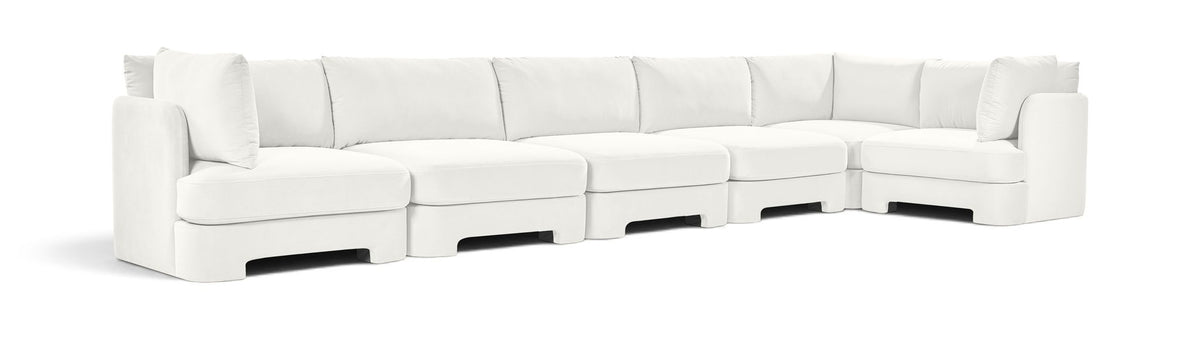 White velvet L-shaped sectional sofa with deep seats and tufted back cushions.