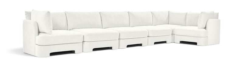 White velvet L-shaped sectional sofa with deep seats and tufted back cushions.