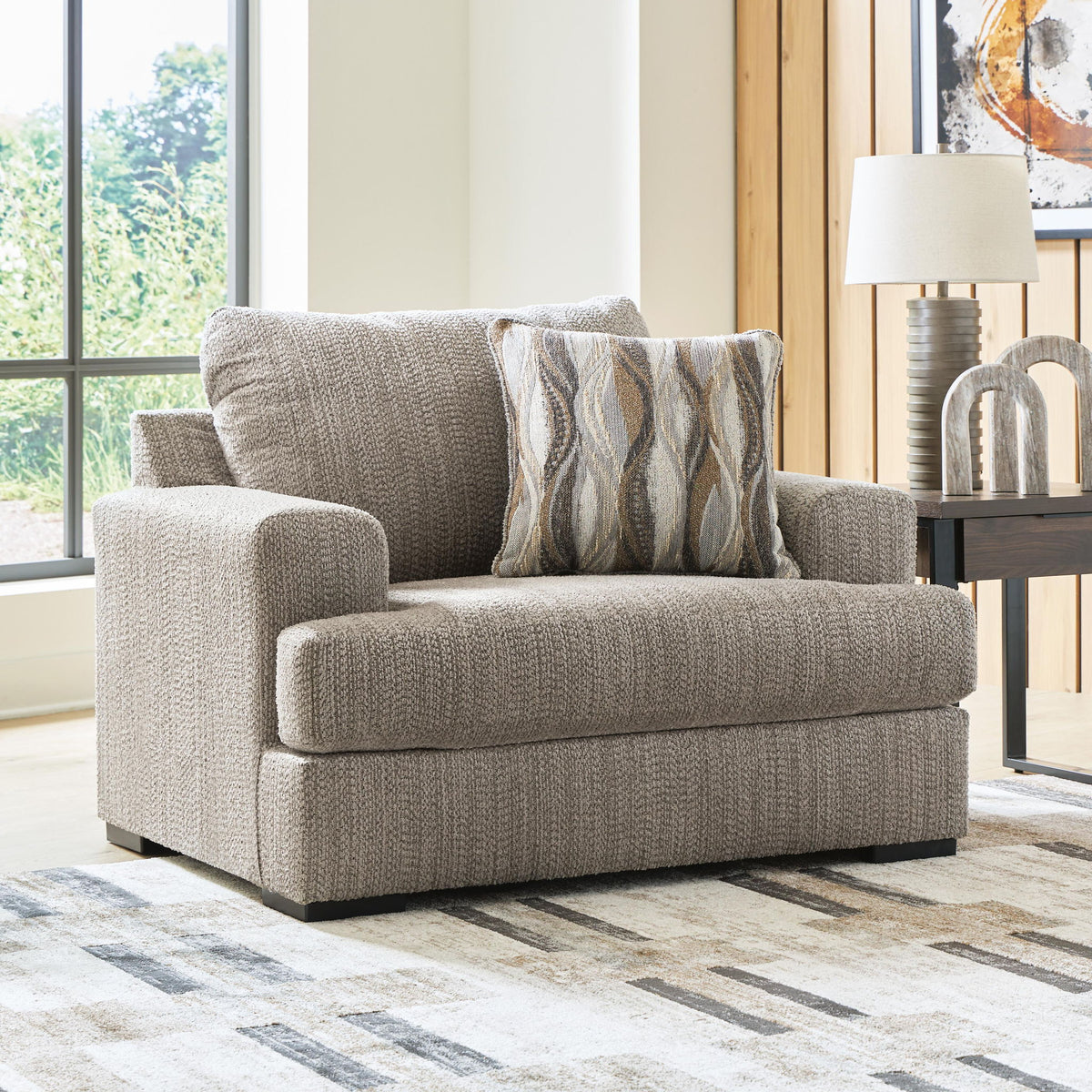 Gray chair and a half with textured upholstery and patterned throw pillow