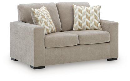 Light beige fabric loveseat with two patterned throw pillows and block feet