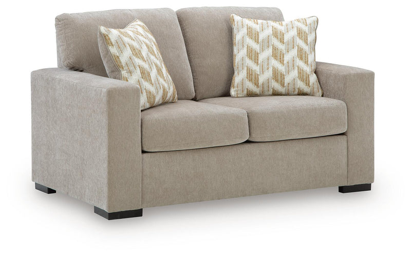 Light beige fabric loveseat with two patterned throw pillows and block feet