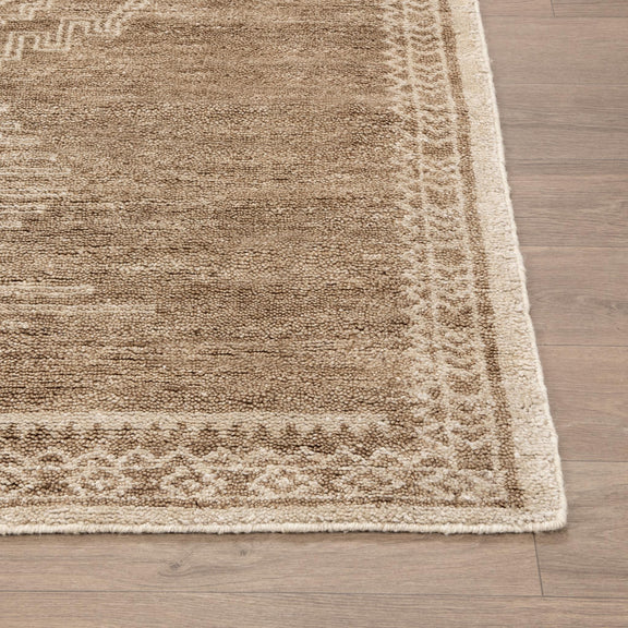 Desert brown rug corner with light geometric border and textured pile.