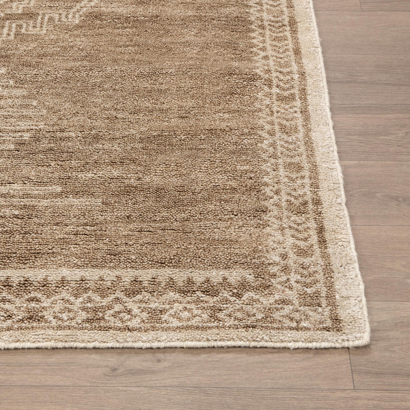 Desert brown rug corner with light geometric border and textured pile.