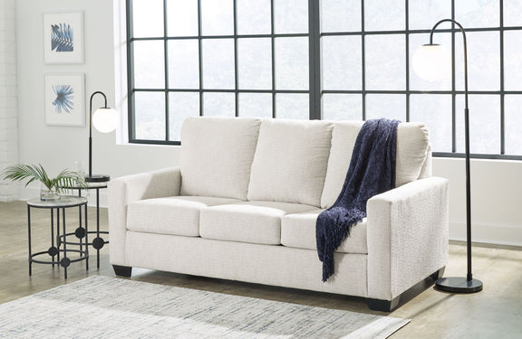Beige fabric sofa with three seat cushions and folded throw on right arm