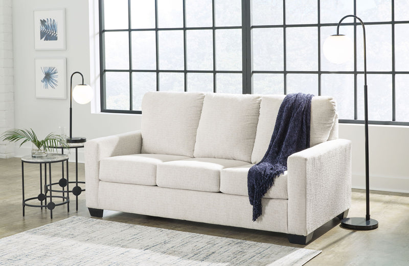 Beige fabric sofa with three seat cushions and folded throw on right arm