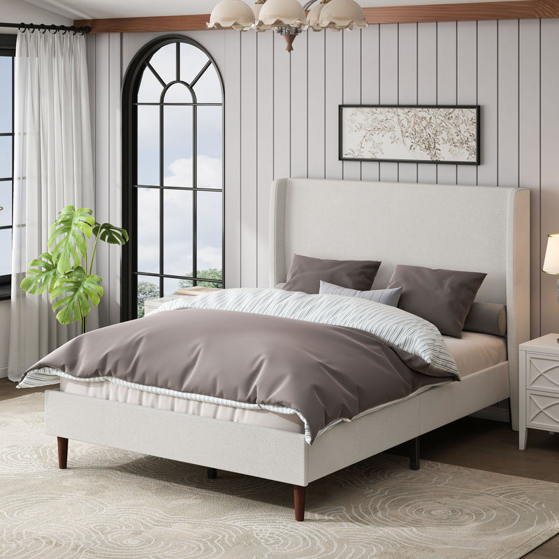 Beige upholstered bed with tall headboard and gray bedding