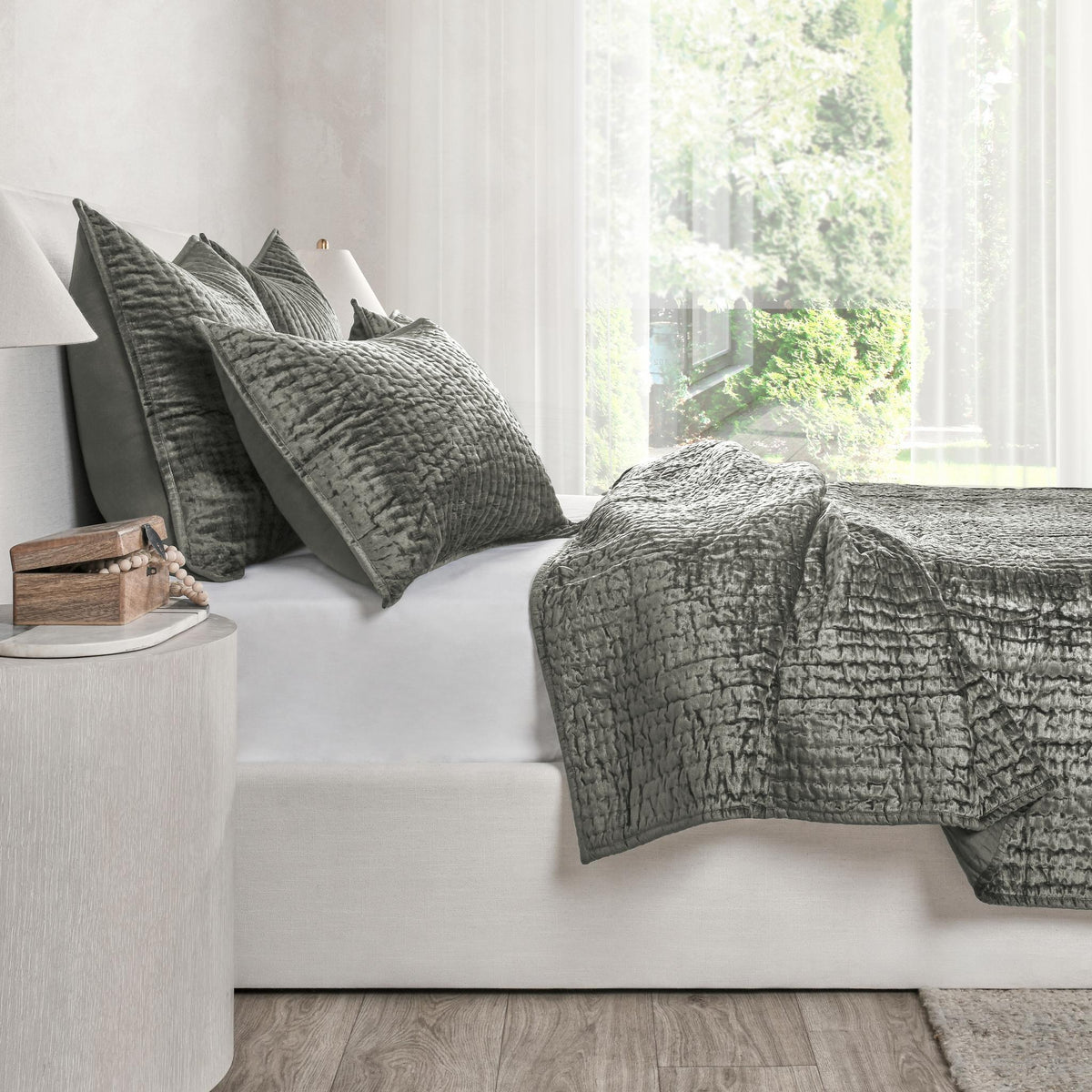Gray velvet quilt set on a white sofa, featuring a textured quilt and pillow shams.