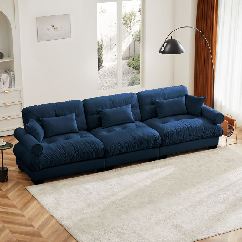 Blue oversized sofa with deep tufted cushions, rounded arms, and matching throw pillows