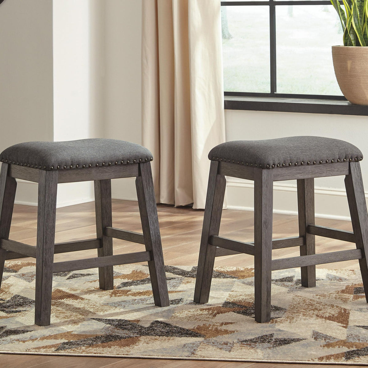 Gray upholstered bar stools with round seats and studded edges