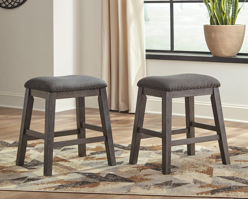 Gray upholstered bar stools with round seats and studded edges
