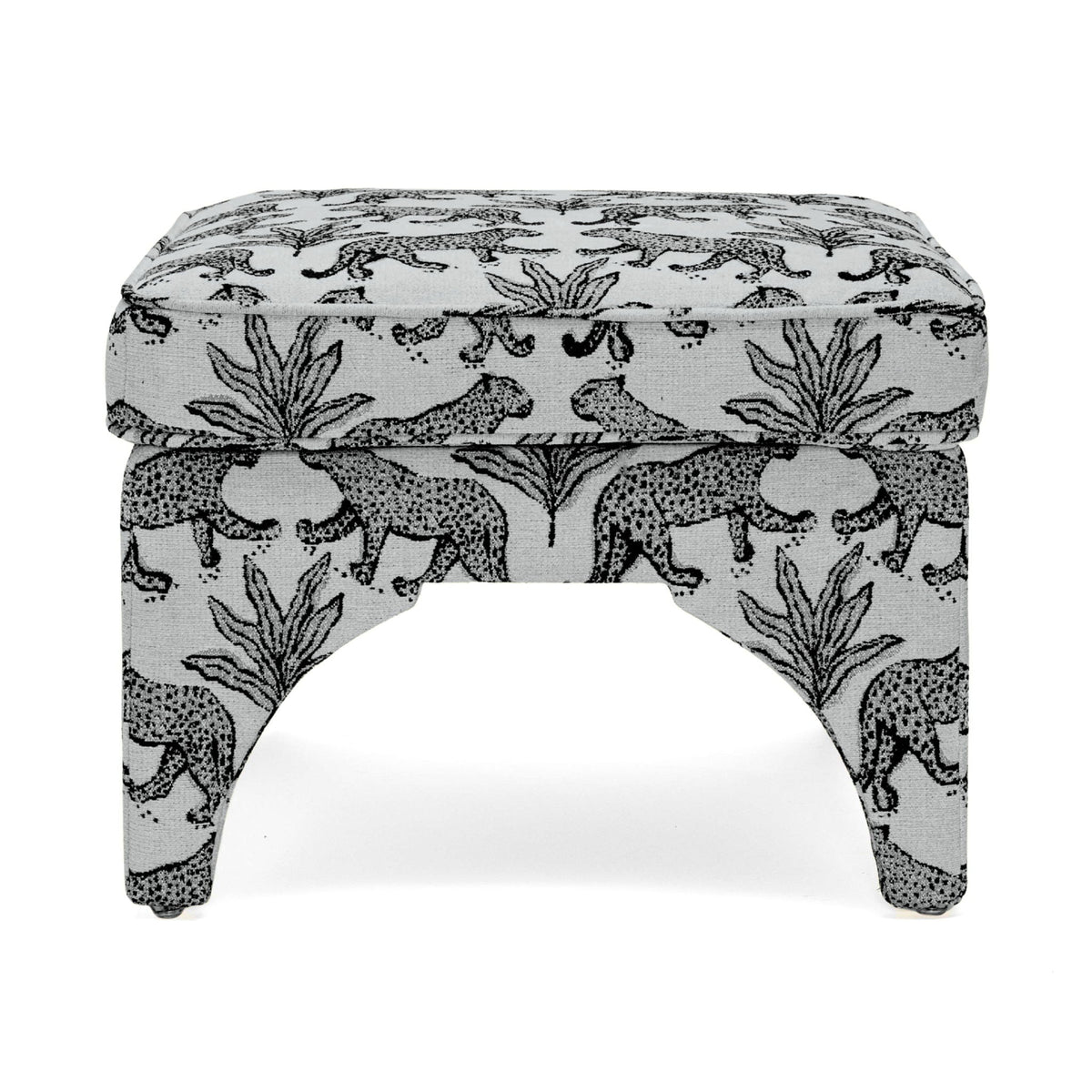 Upholstered ottoman with white fabric and black jungle animal pattern, arched legs, padded top
