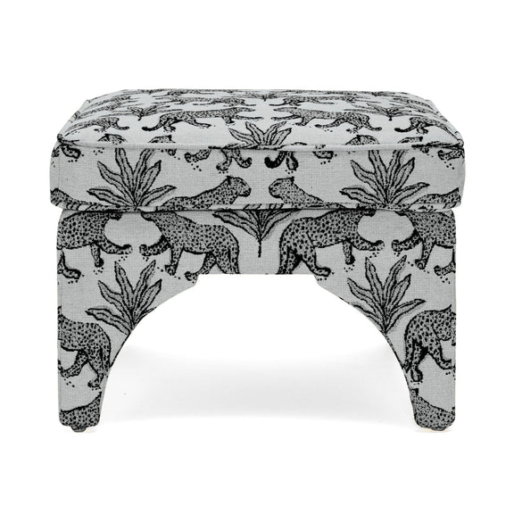 Upholstered ottoman with white fabric and black jungle animal pattern, arched legs, padded top