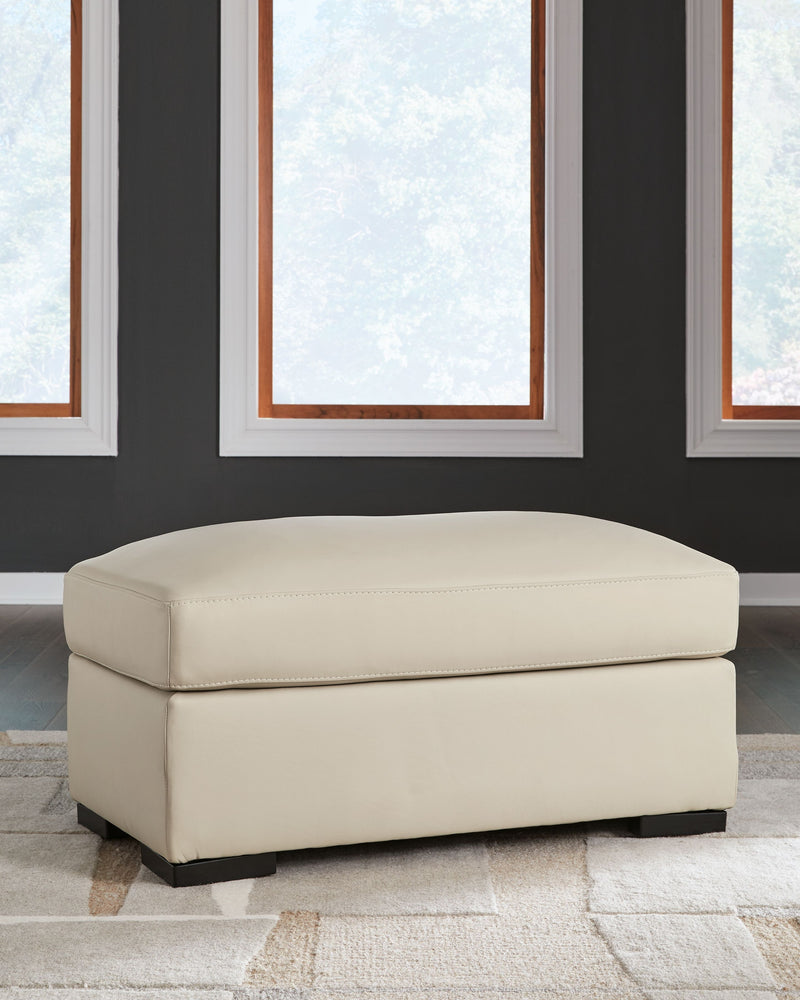 Almond upholstered ottoman, horizontal view showing cushioned seat and block legs