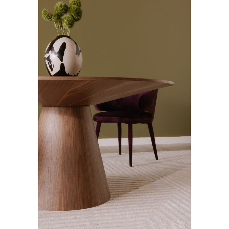 Round walnut dining table with central pedestal base beside upholstered chairs