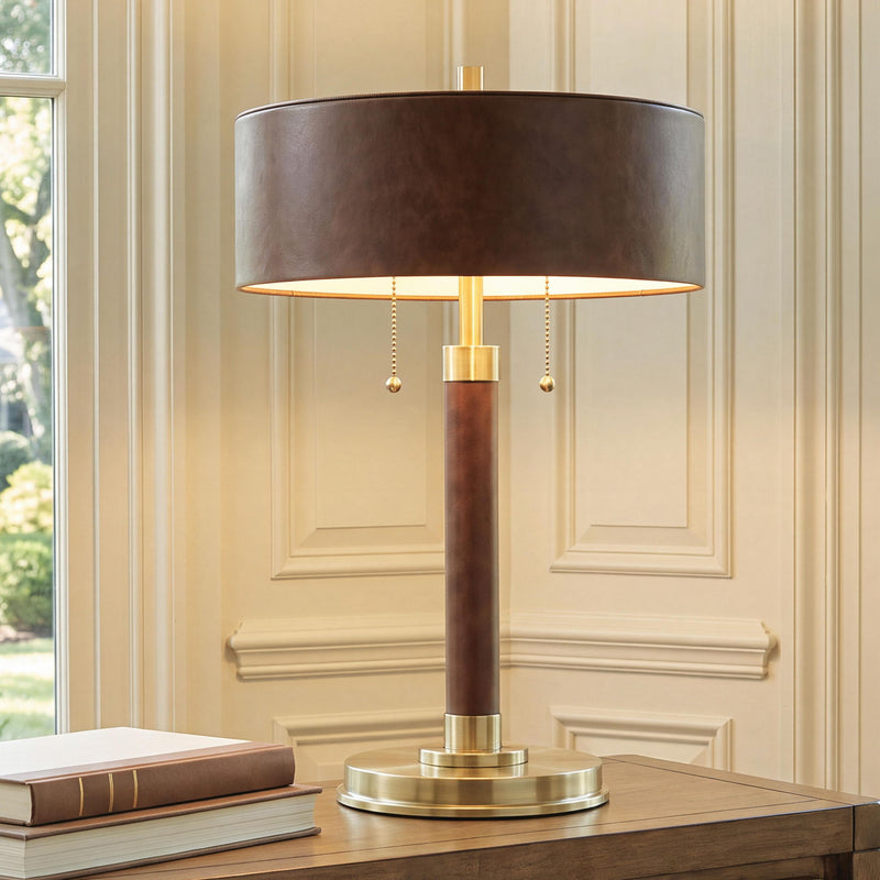 Brown metal table lamp with gold stand and glowing drum shade