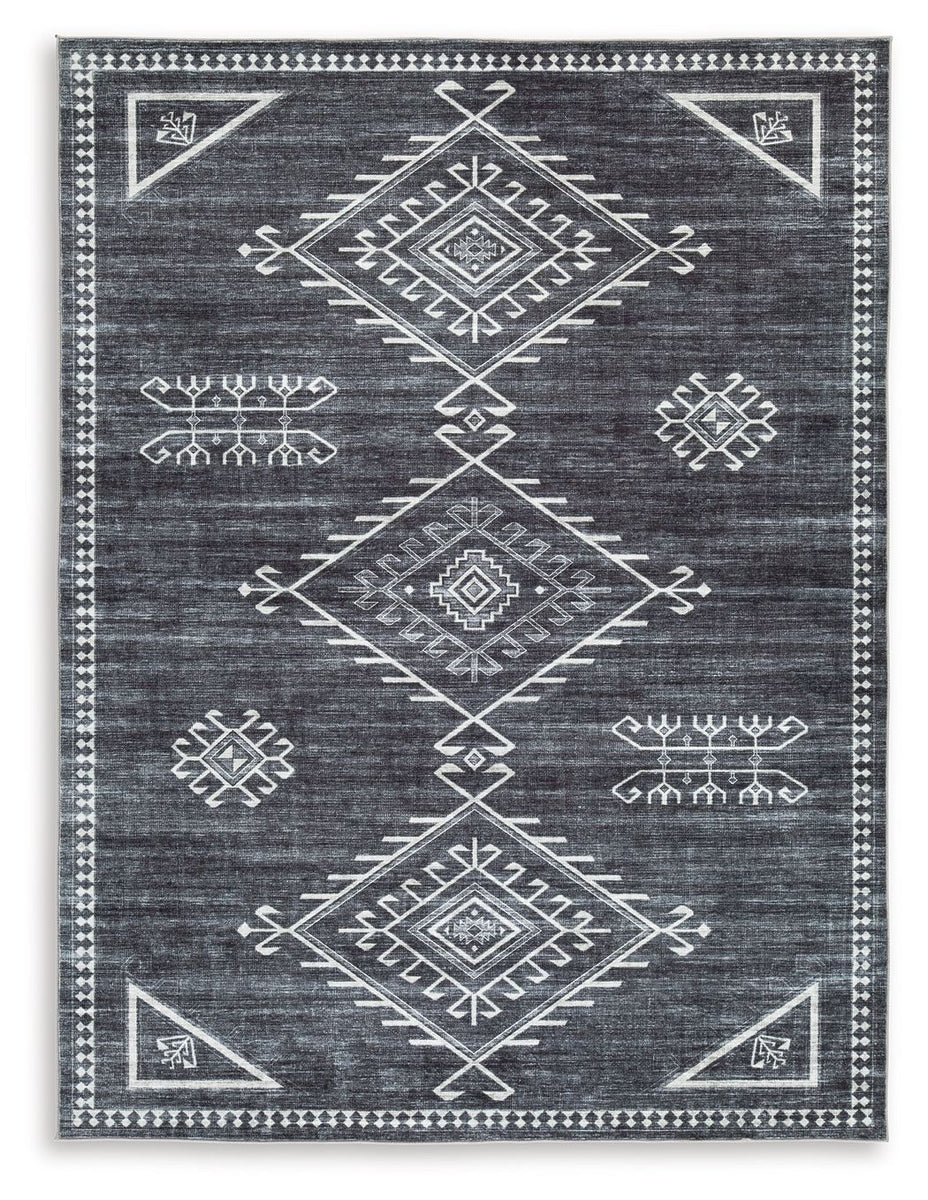 Black area rug with cream and gray geometric motifs, bordered with small bead trim