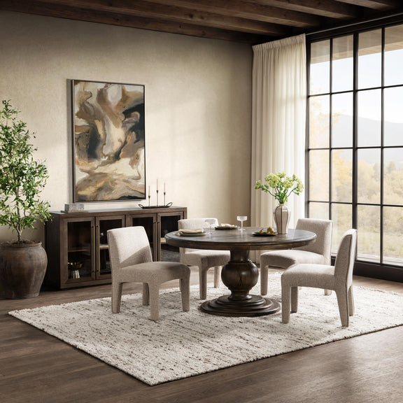 Round dark brown dining table with pedestal base set in a living room seating area